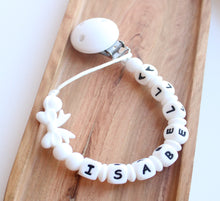 Load image into Gallery viewer, White pacifier clip with letter beads on a wooden board

